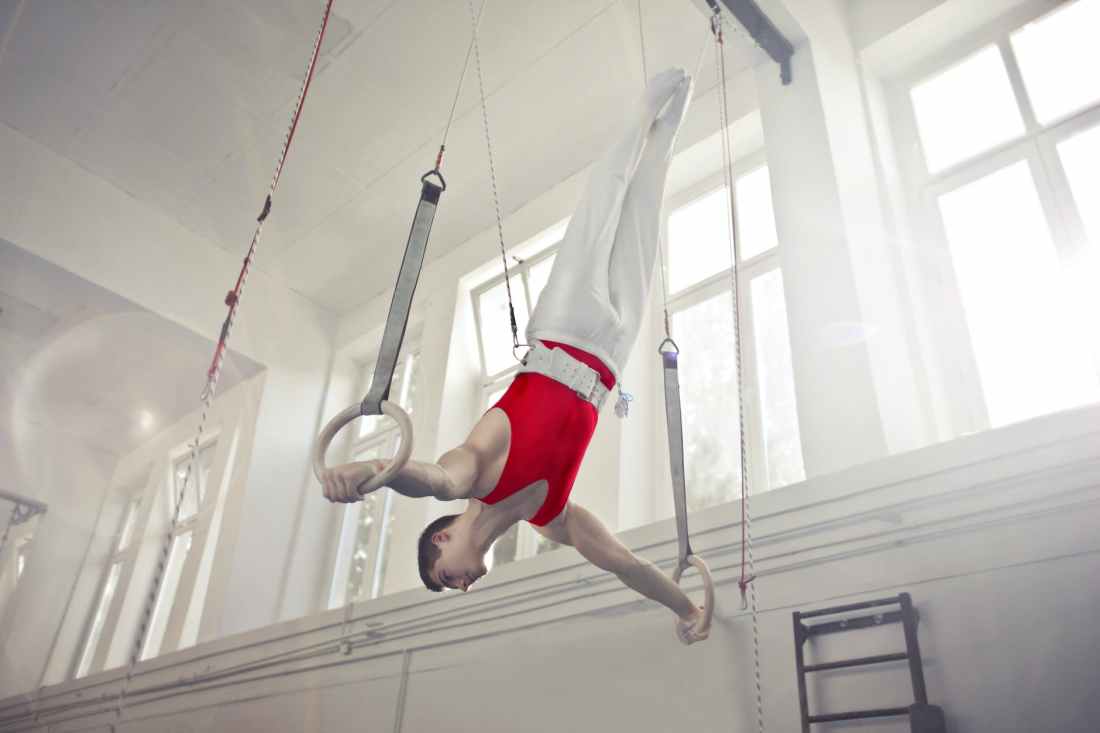 photo of male gymnast practicing on gymnastic rings
